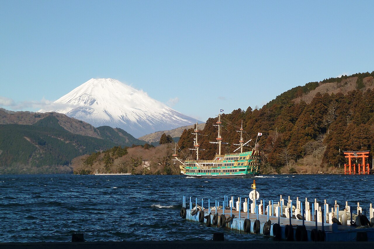 Fuji hinter dem Ashi-See, ein Ausflugsboot und das Schrein-Tor am Seeufer in Hakone, Japan.