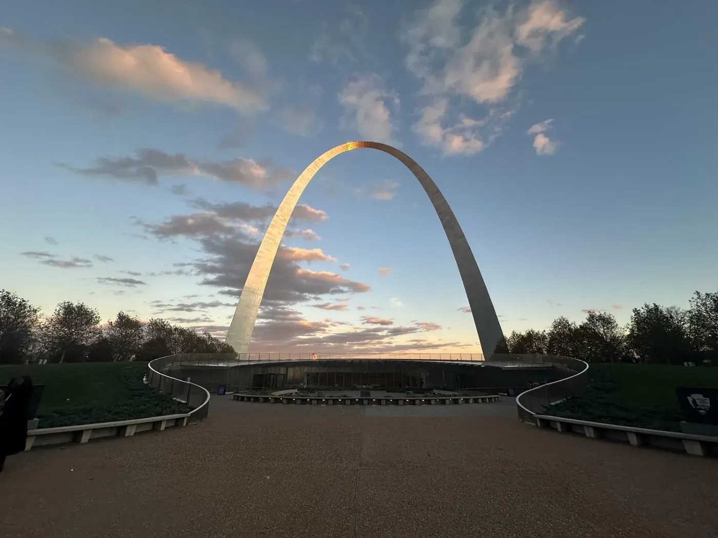 The Gateway Arch rising above its landscaped grounds at sunset in St. Louis.