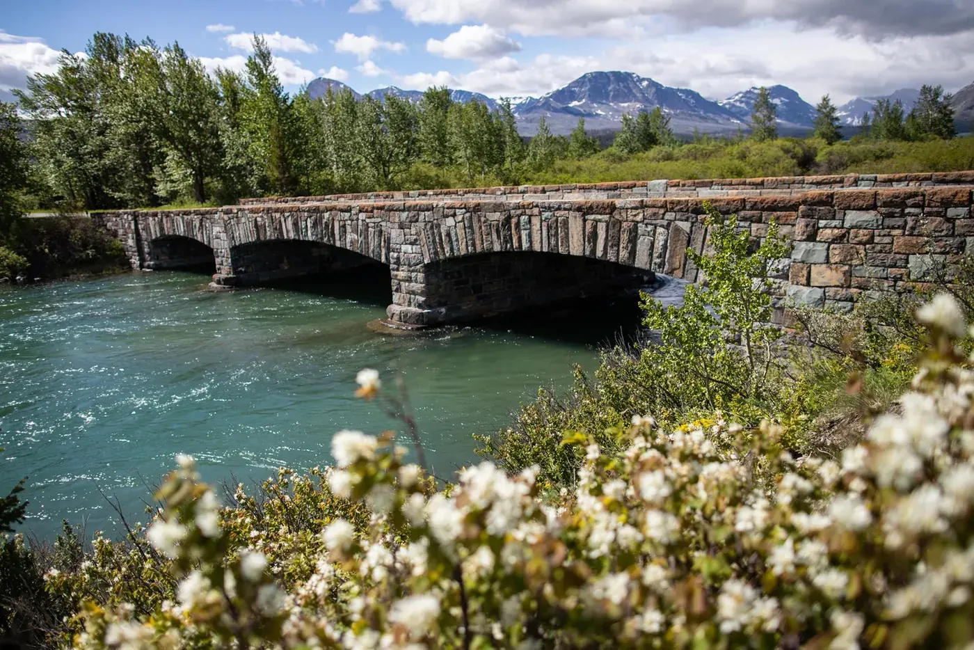 A stone bridge over a turquoise river along Going-to-the-Sun Road in Glacier National Park.
