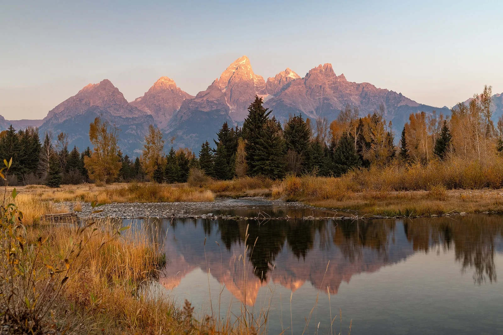 The Teton Range lit by sunrise and reflected in water at Schwabacher Landing.