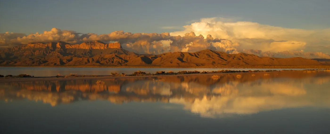 The Guadalupe Mountains reflected in seasonal water across the salt flats.