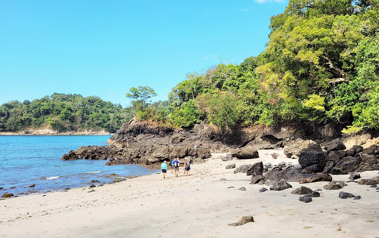 Praia de areia e promontório coberto de floresta no Parque Nacional Manuel Antonio, Costa Rica.