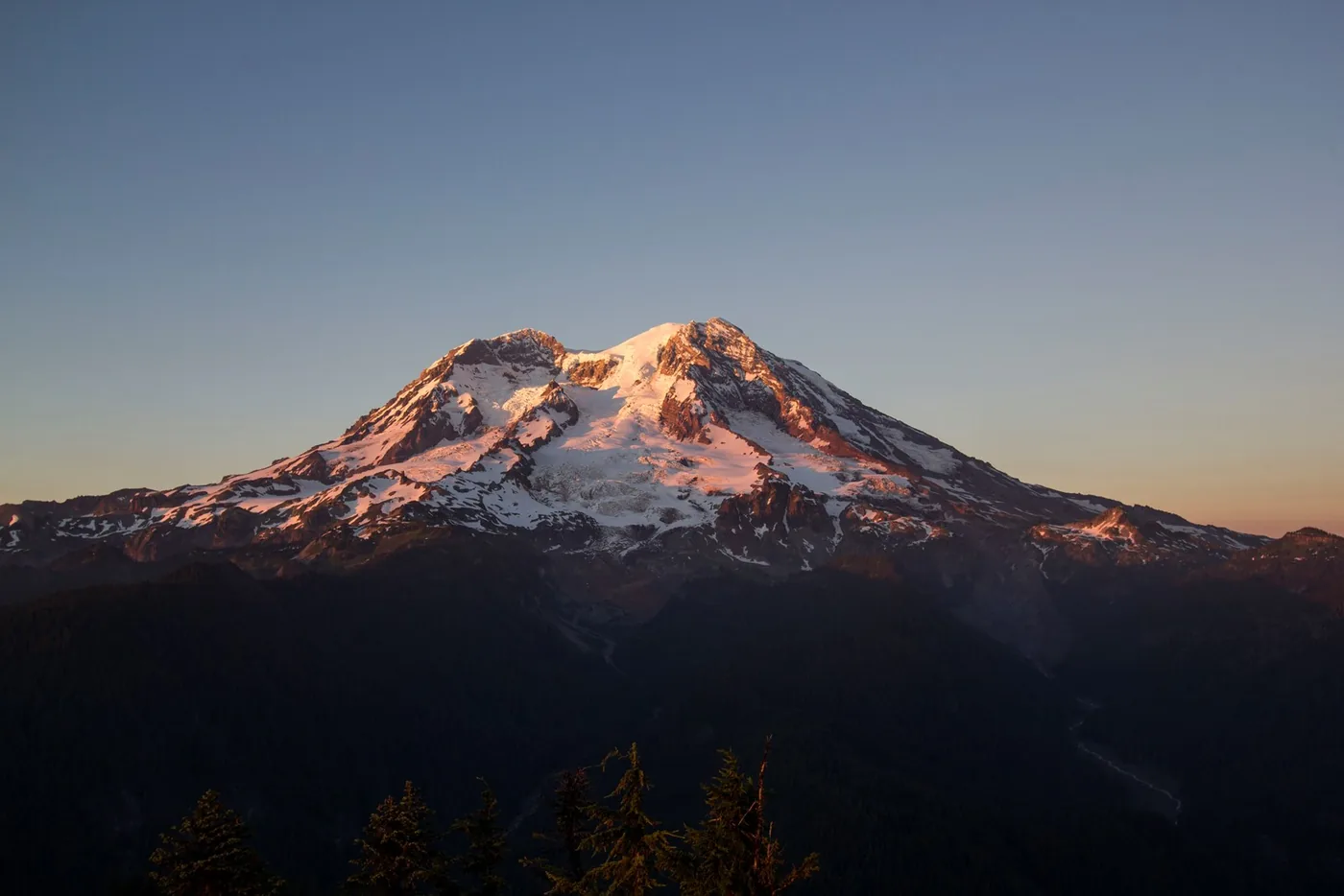 Sunset lighting the snowy summit and glaciers of Mount Rainier.