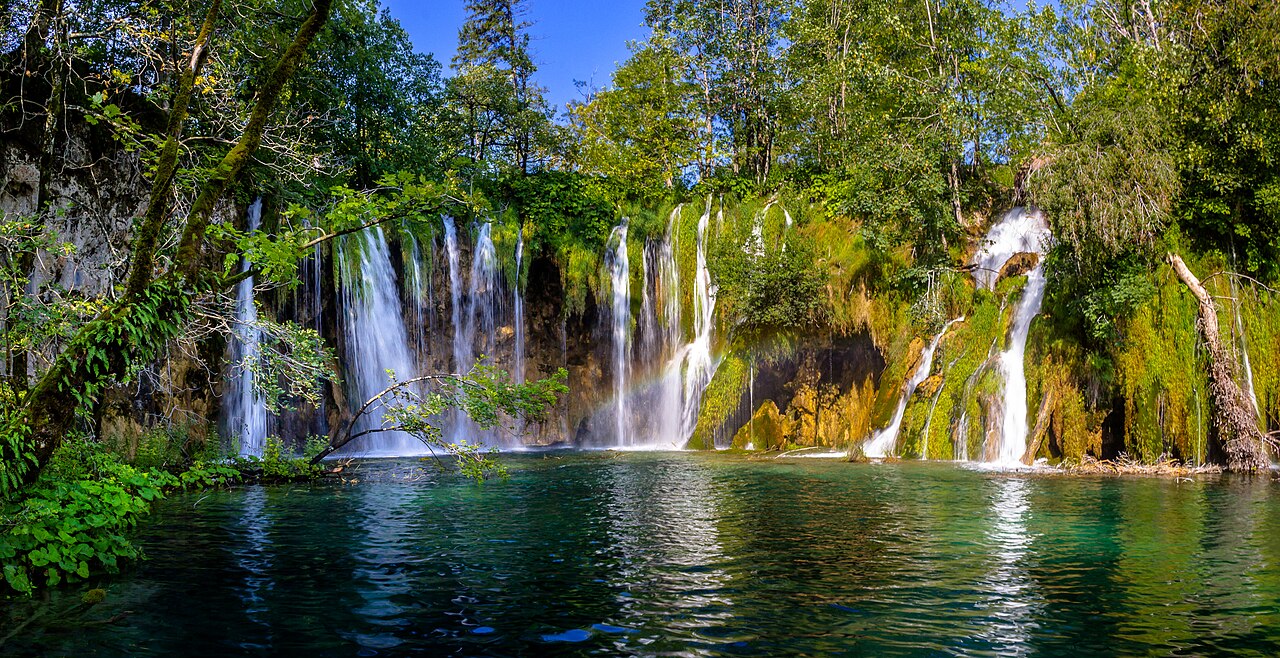 Watervallen die uitkomen in een meer tussen de bossen in nationaal park Plitvicemeren, Kroatië.