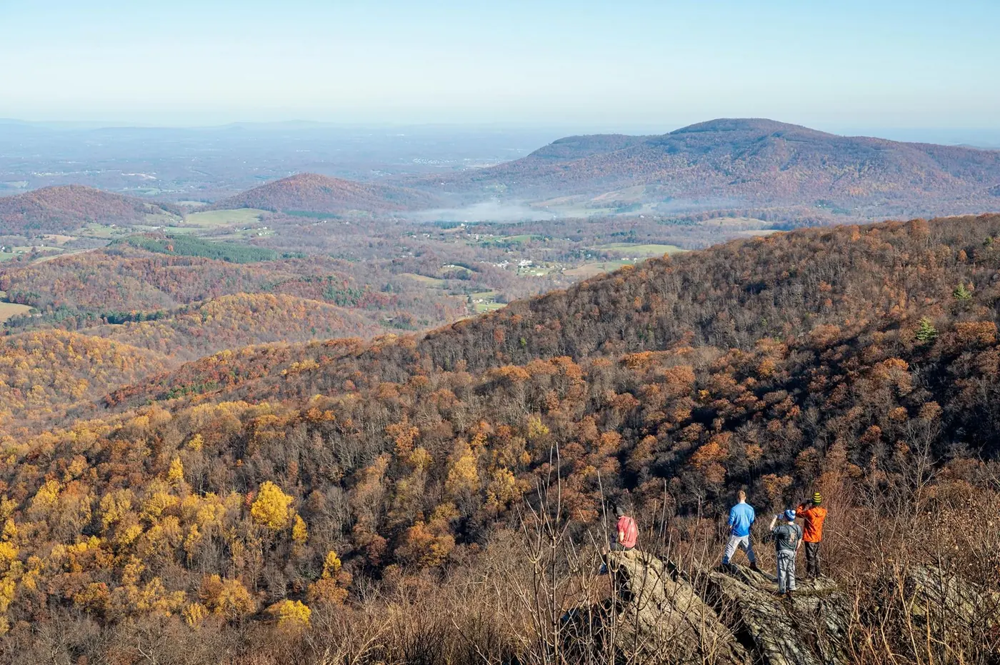 Visitors overlooking rolling autumn-colored mountains in Shenandoah National Park.